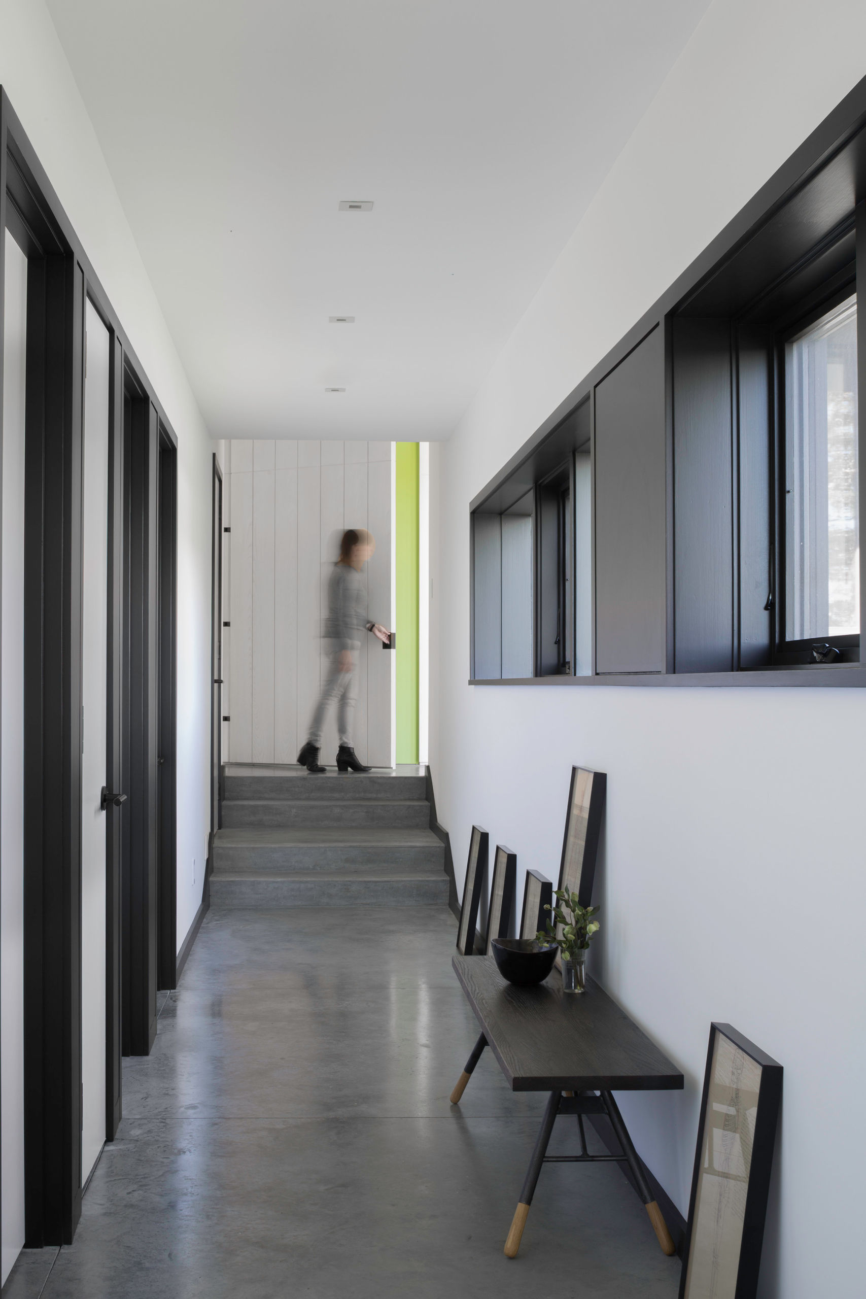 Looking down the hallway in the bedroom wing, with polished concrete floor and row of high windows along right side