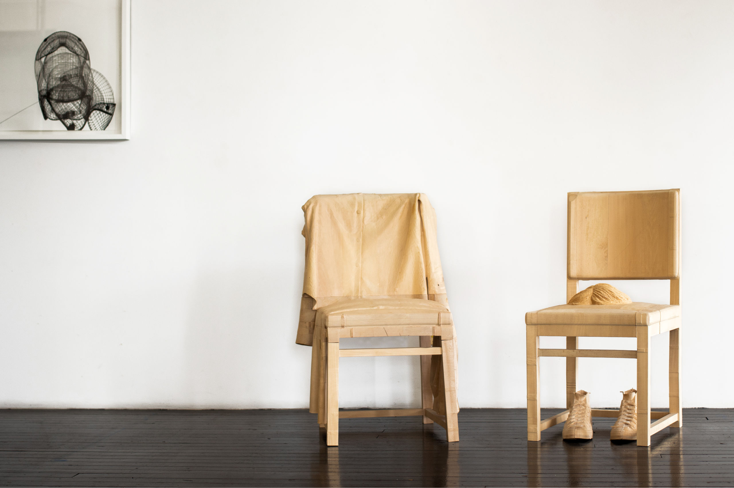 Wood sculpture of two chairs and shows next to black and white print, by Jonathan Brand.